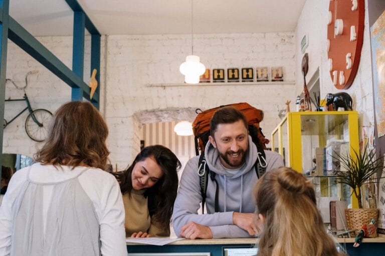 Backpackers checking in at a hostel reception desk.