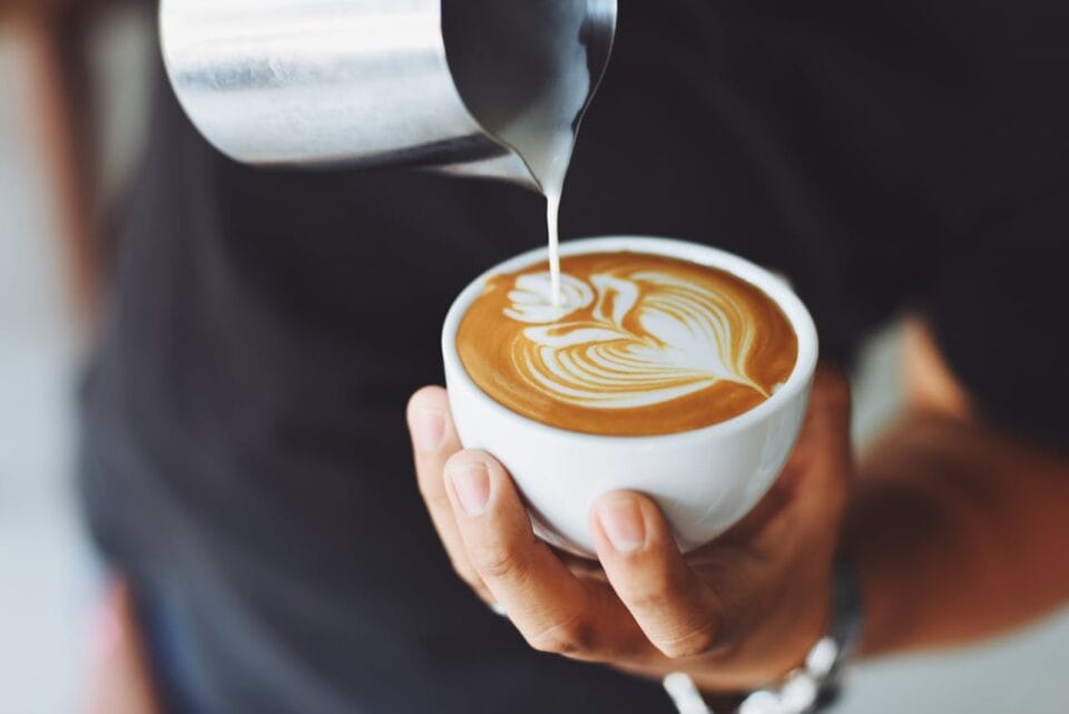 Barista verse du lait dans un cappuccino artistique