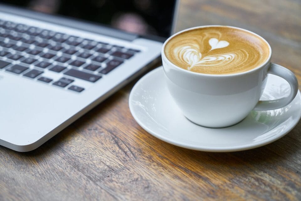 Café cappuccino près d'un ordinateur portable