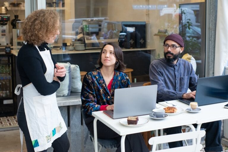Waitress talking to two customers in a café