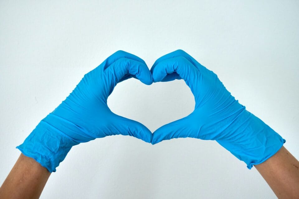 Mains en gants bleus formant un cœur