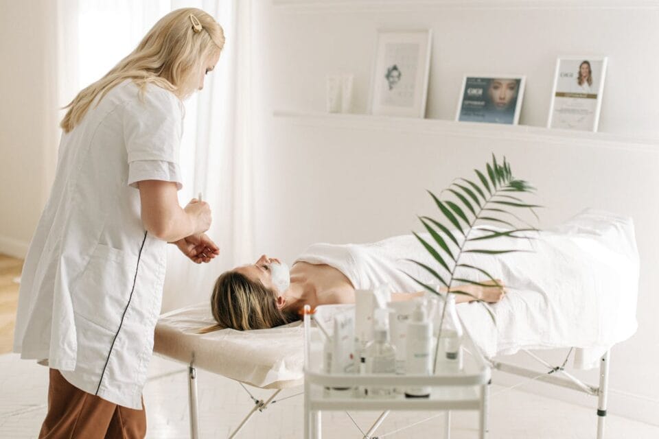 Esthéticienne appliquant masque facial à cliente relaxée