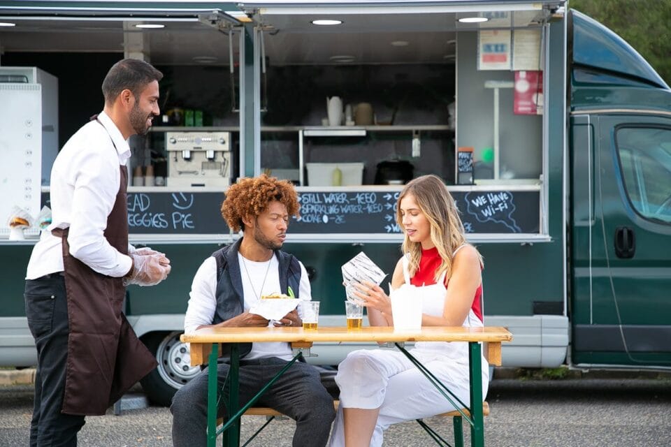 Couple déjeune, serveur souriant, camion-resto en arrière-plan