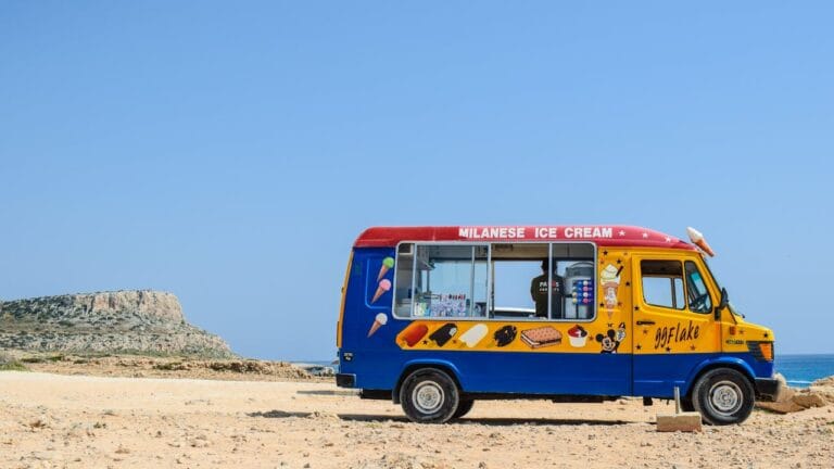 Colourful ice cream van by rocky beach