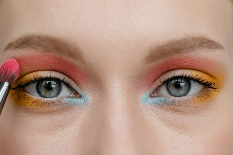 Yeux maquillés en rouge et bleu appliquant pinceau