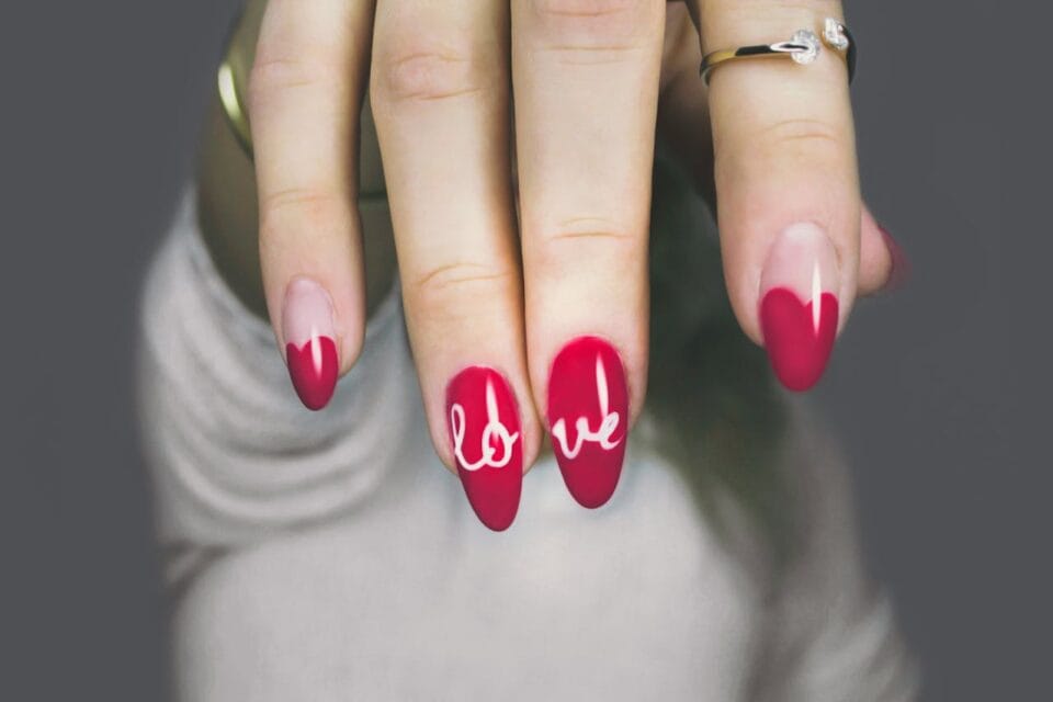 Ongles rouges avec le mot 'love' écrit dessus