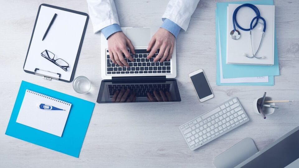 Médecin utilisant un ordinateur, stéthoscope et lunettes visibles