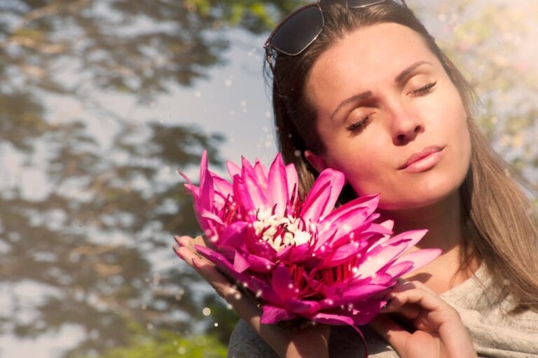 Femme tenant une fleur de lotus rose au soleil