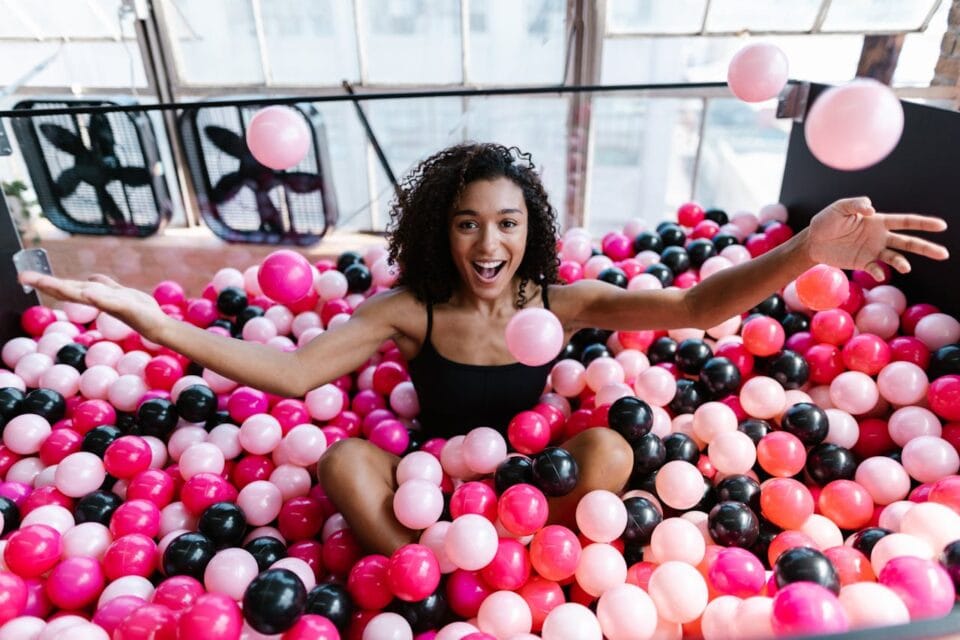 Femme joyeuse dans une piscine de balles roses et noires