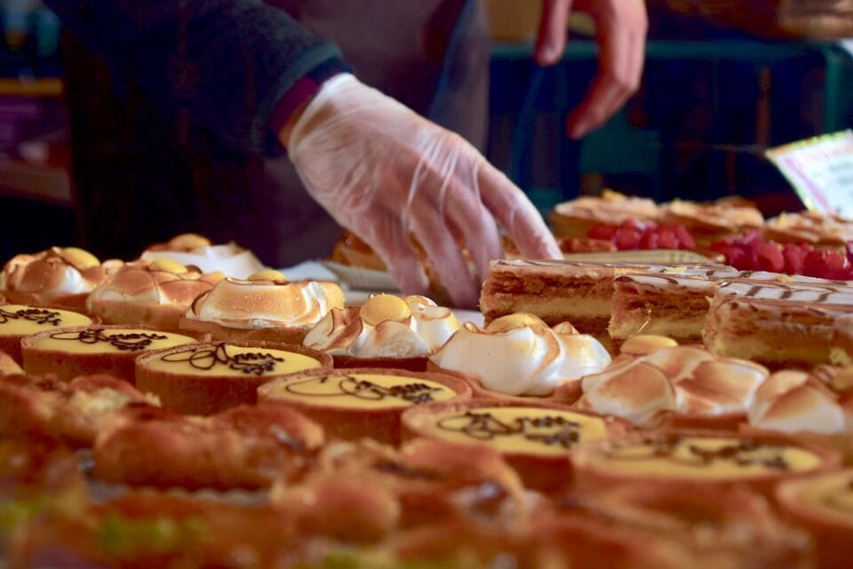 Pâtisseries variées servies par vendeur avec gants