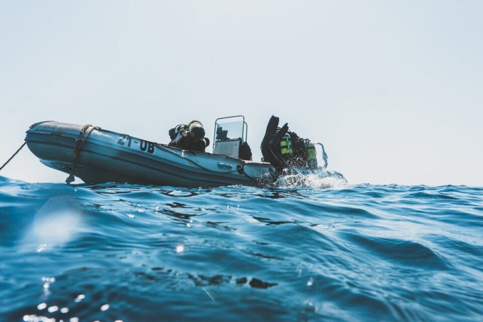 Plongeurs entrant dans l'eau depuis un bateau pneumatique