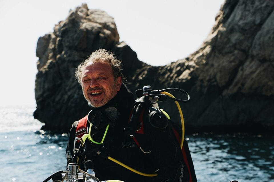 Plongeur souriant équipé près d'un rocher marin
