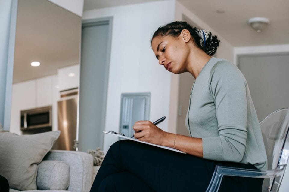 Femme concentrée écrivant dans un cahier chez elle