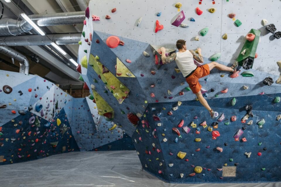Homme escaladant un mur d'escalade intérieur coloré