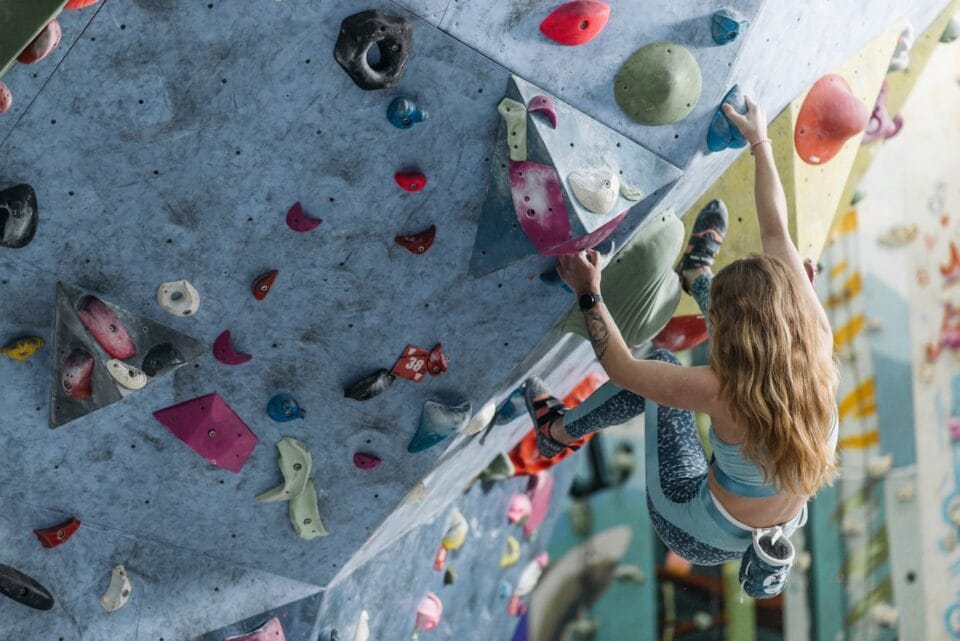 Femme escaladant un mur d'escalade intérieur coloré