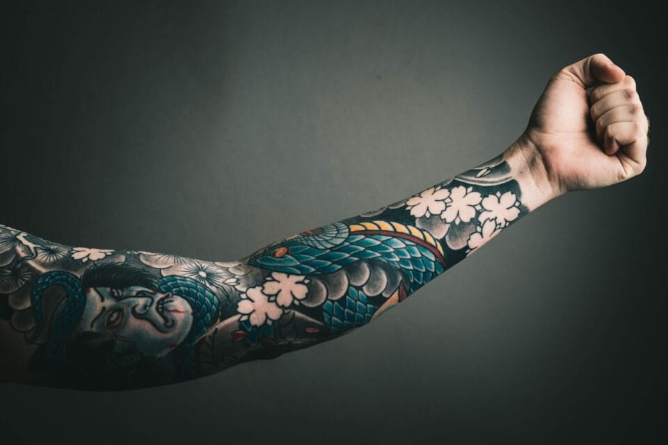 Bras tatoué avec des motifs colorés sur fond sombre