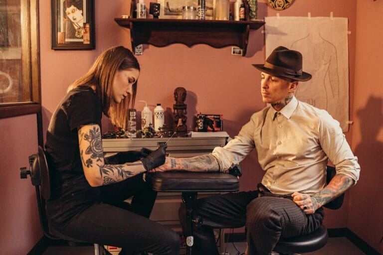Tatoueuse travaillant sur bras d'un homme élégant