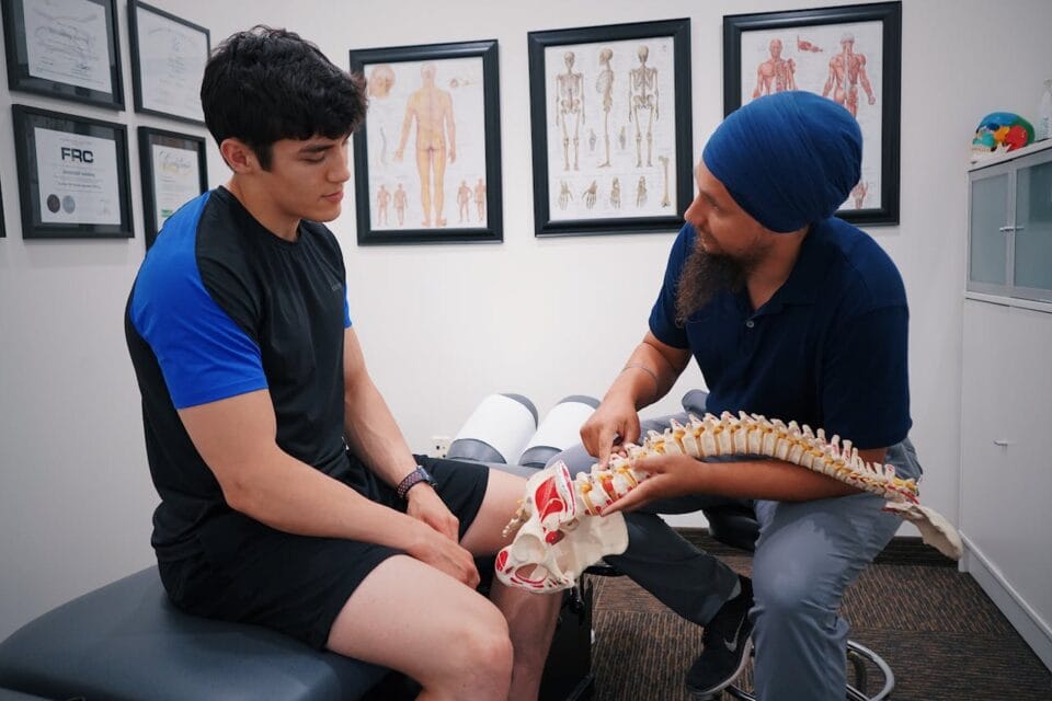 Kinésithérapeute expliquant modèle de colonne vertébrale à patient