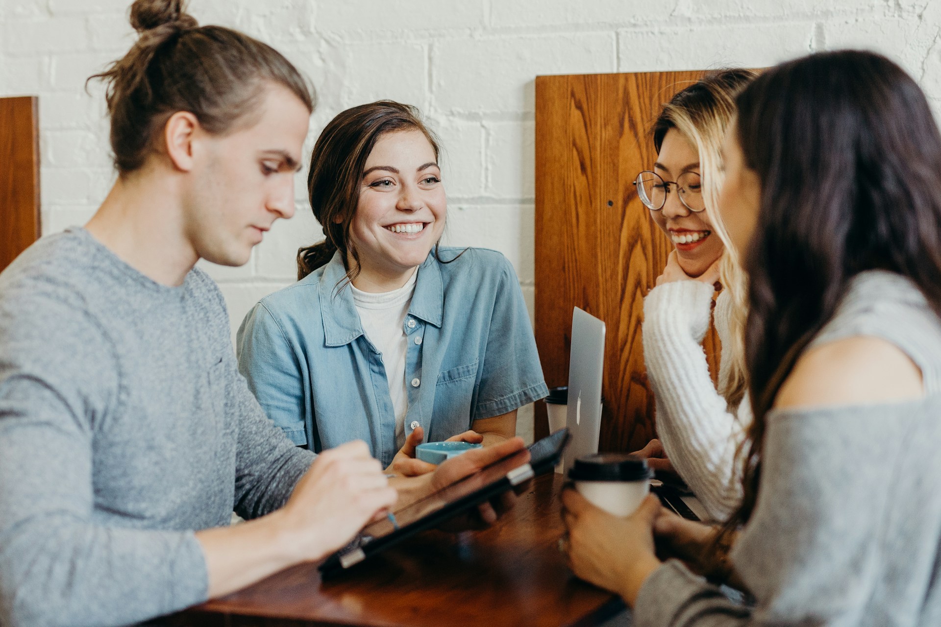Quatre jeunes adultes discutent autour d’une table avec ordinateurs