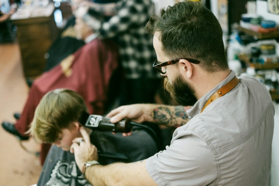 Barbier tatoué coupant les cheveux d'un enfant
